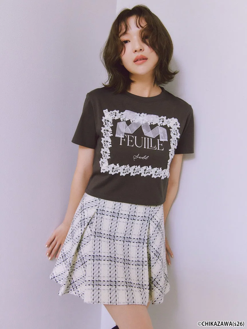 黒いTシャツと白いチェック柄のプリーツスカートを着用した女性モデル