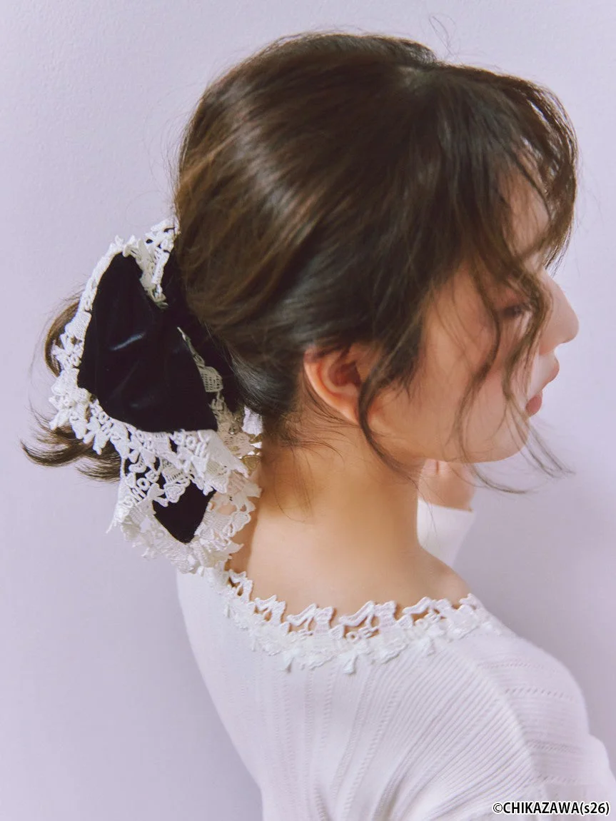 黒いベルベットのリボンと白いレースで飾られたヘアスタイルが特徴の女性の横顔