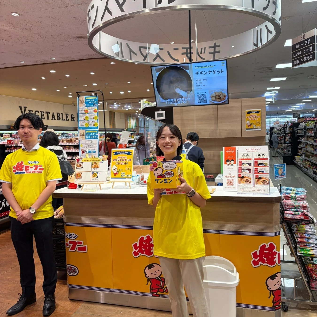 スーパーマーケットの食品売り場で、ケンミン焼ビーフンのプロモーションイベントが開催されている様子。スタッフがレシピを紹介している