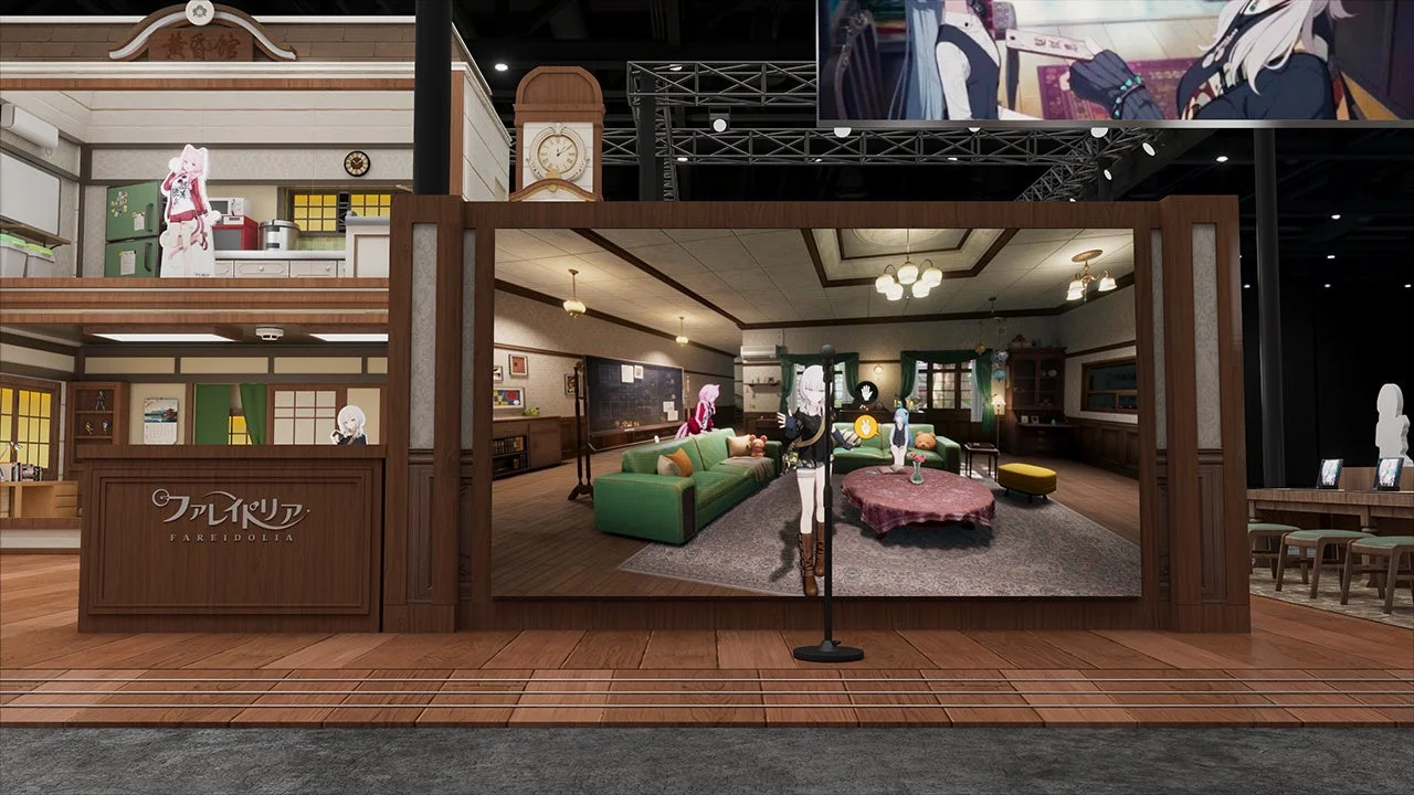 バーチャル空間の展示ブースの様子。アニメキャラクターの等身大パネルが複数配置され、リビングルームやキッチンといった異なる部屋のセットが再現されている。上部には関連映像が映るスクリーンも見られる。