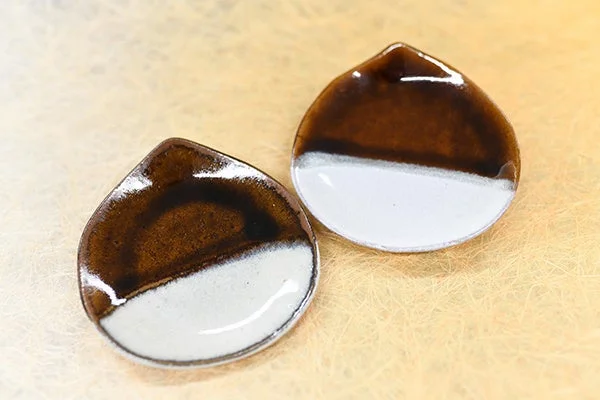 茶色と白のツートンカラーの釉薬が施された、しずく型の陶器の小皿が2枚