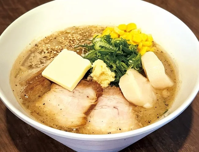バターとコーン、チャーシュー、ねぎ、そして白い具材がトッピングされたラーメン