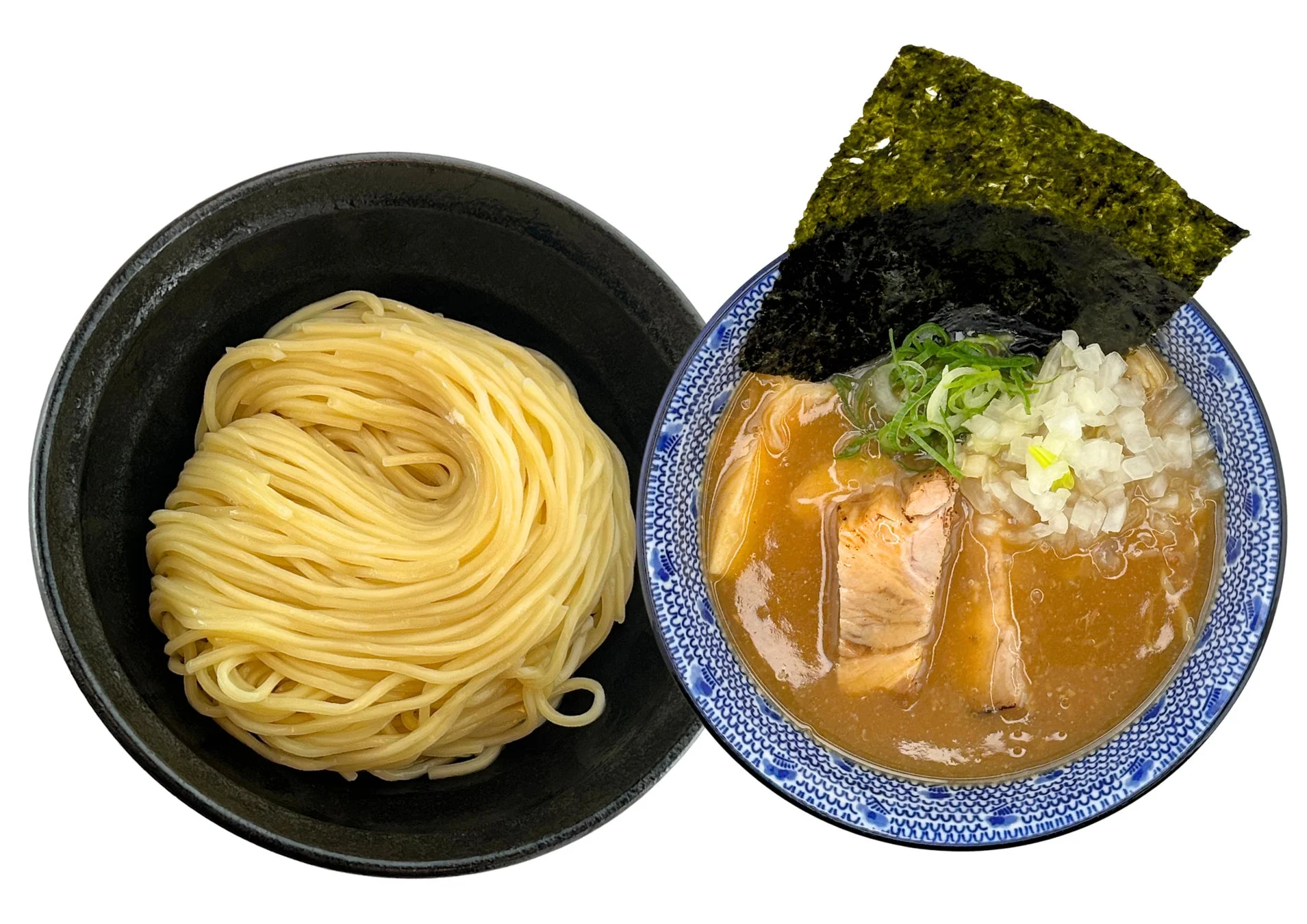 白い背景につけ麺が2つの器に分かれて置かれています。左の器には麺、右の器にはチャーシュー、玉ねぎ、ネギ、海苔がトッピングされた濃厚なつけ汁が入っています。