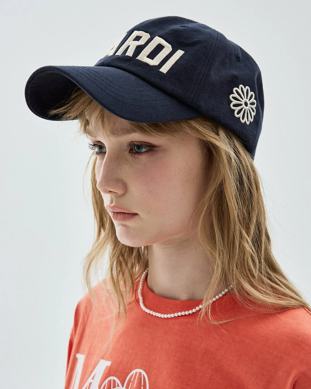 MardiのキャップとオレンジTシャツを着た女性