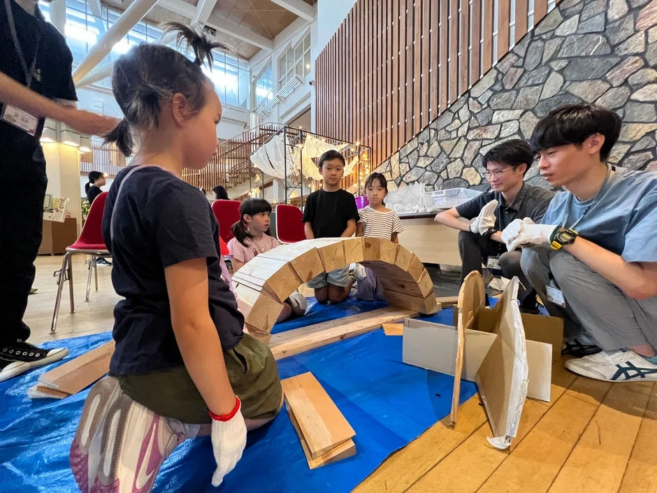 屋内施設で子供たちが木材を使った建築ワークショップに参加しています