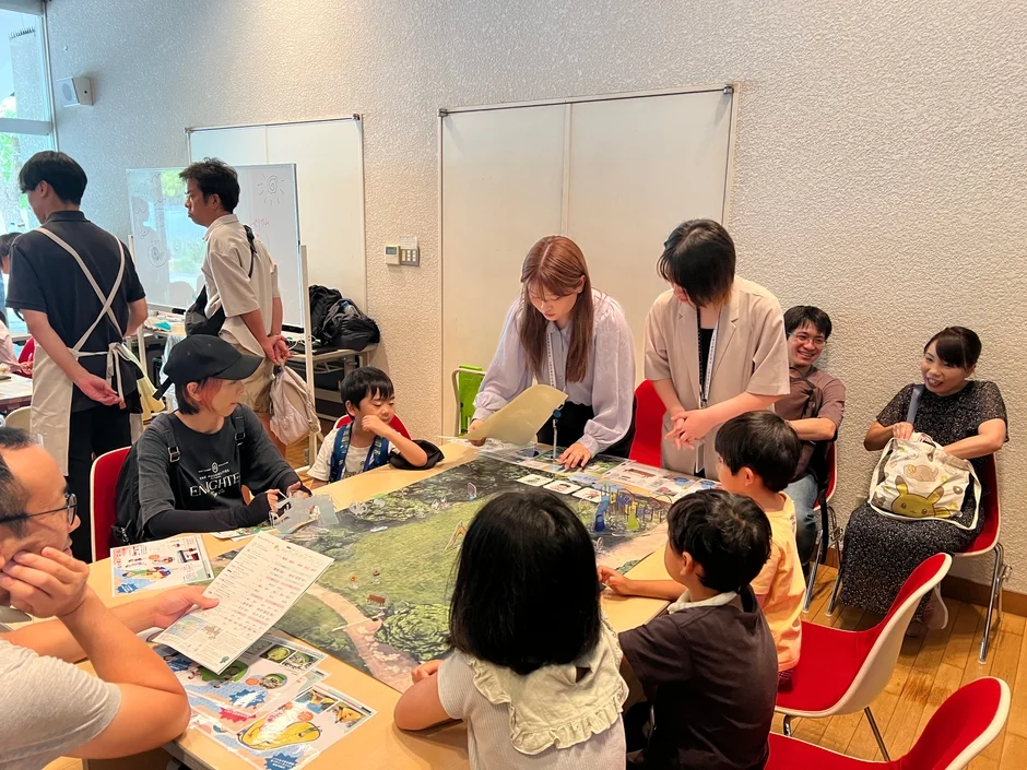 室内で大人と子供たちがテーブルを囲み、ボードゲームや教育的な活動を楽しんでいる様子