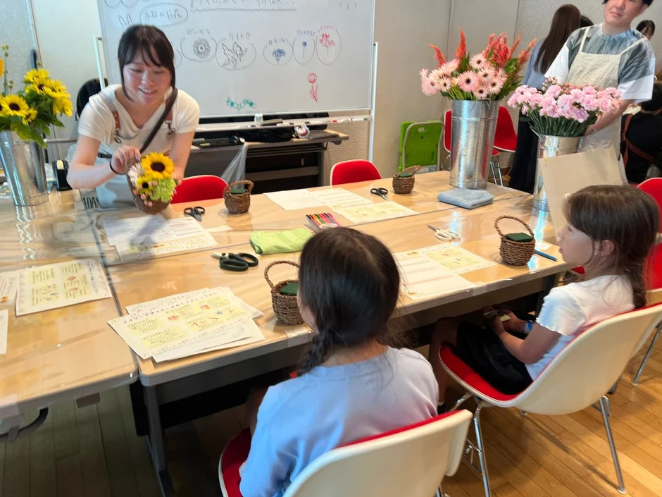 女性が講師となって子供たちにフラワーアレンジメントを教えているワークショップの様子