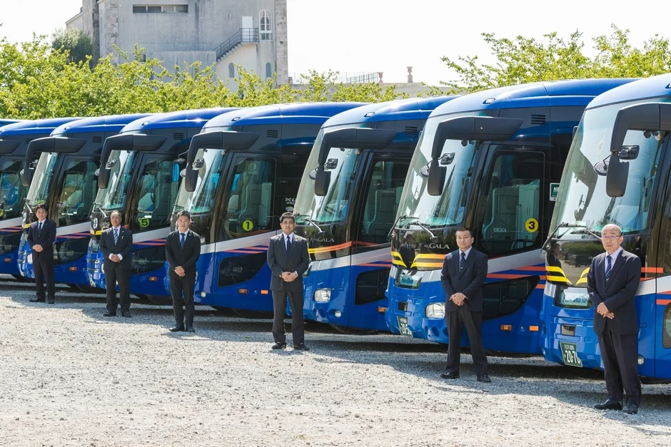 青い大型バスと社員の集合写真