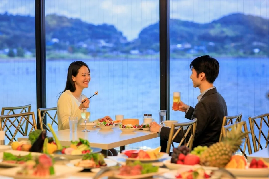 窓から湖を眺めながら食事をするカップル