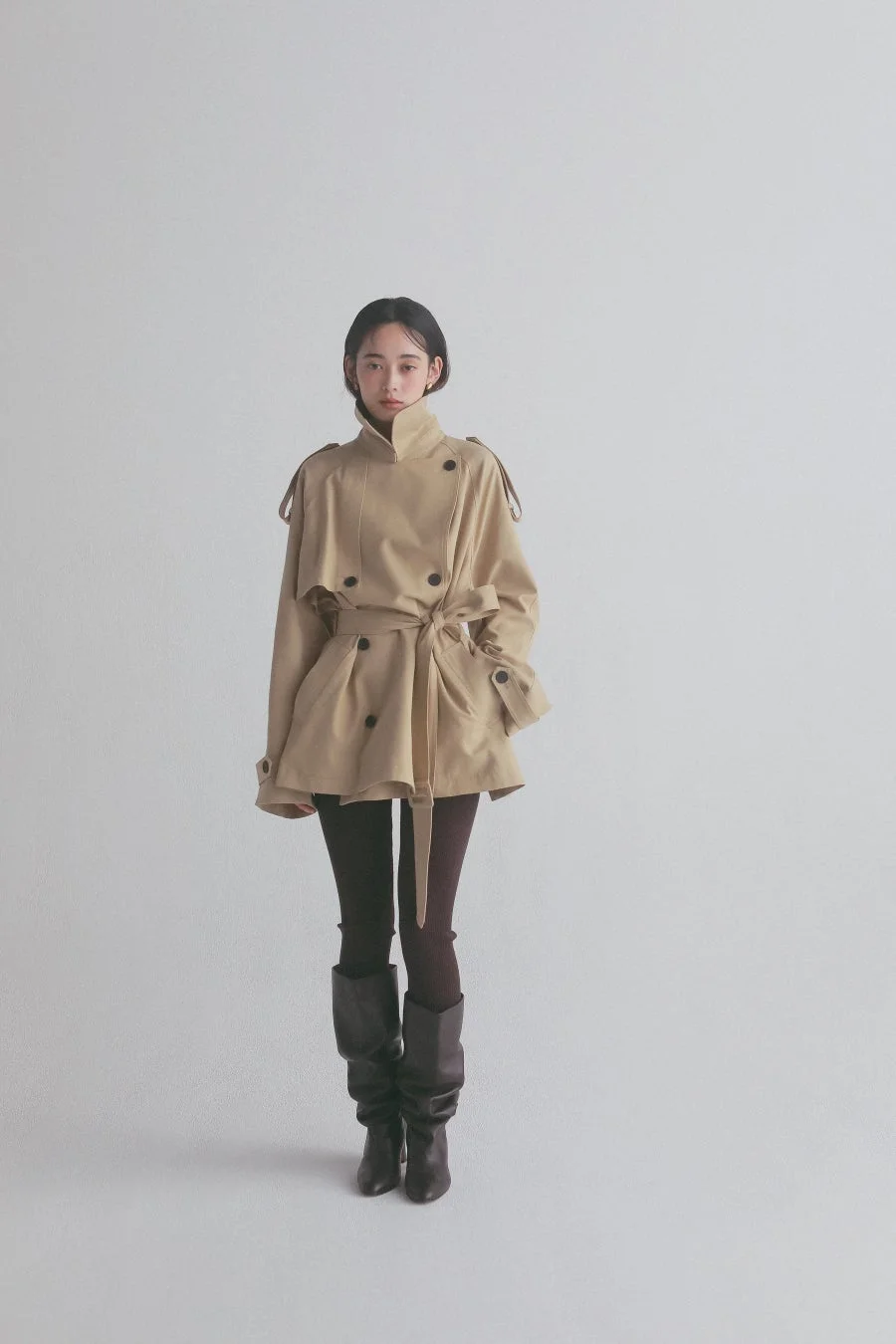 ベージュのショート丈トレンチコートを着用した女性