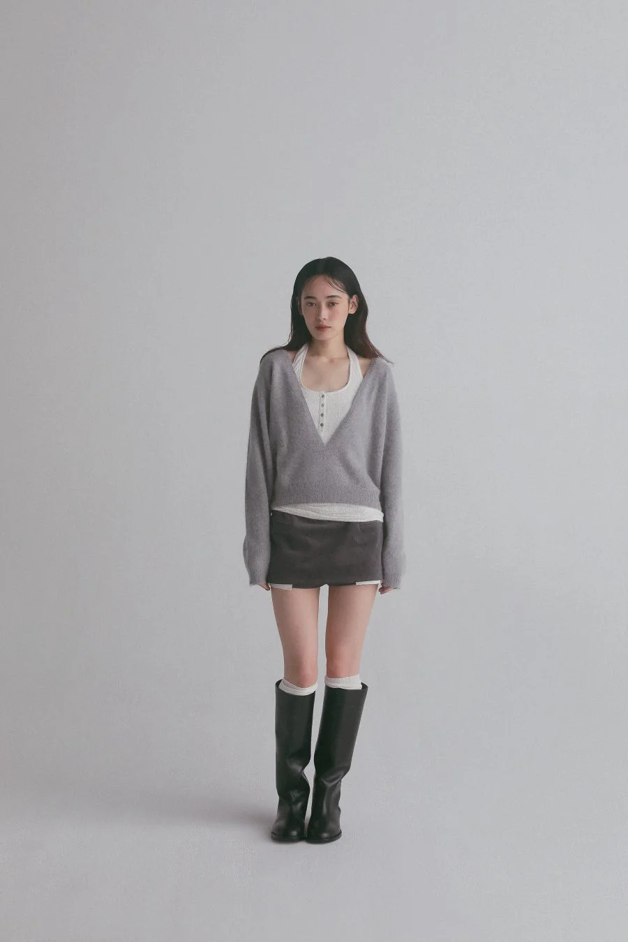 グレーのVネックセーターとミニスカートを着用した女性