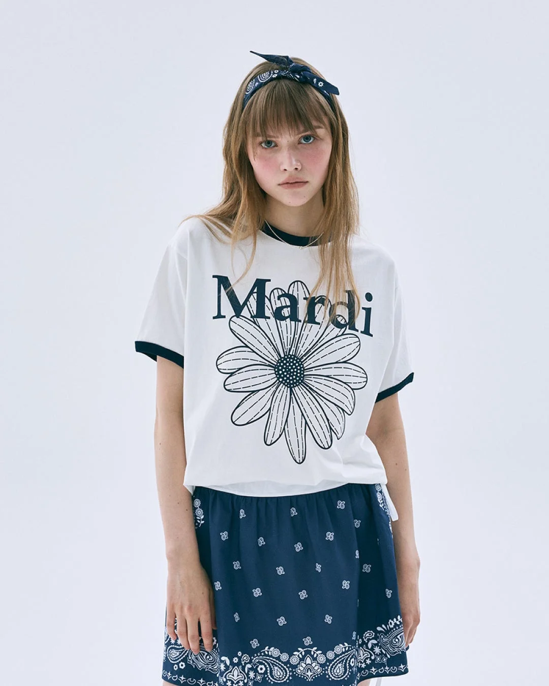 Mardiの白Tシャツとネイビーのスカートを着た女性