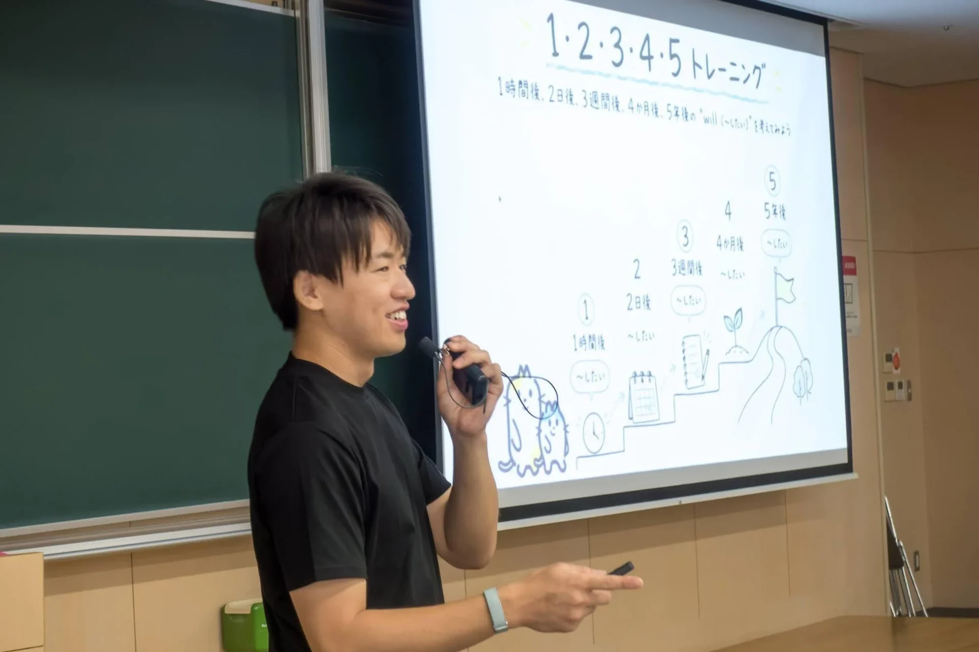 トレーニングに関するスライドを背景にプレゼンテーションを行う男性