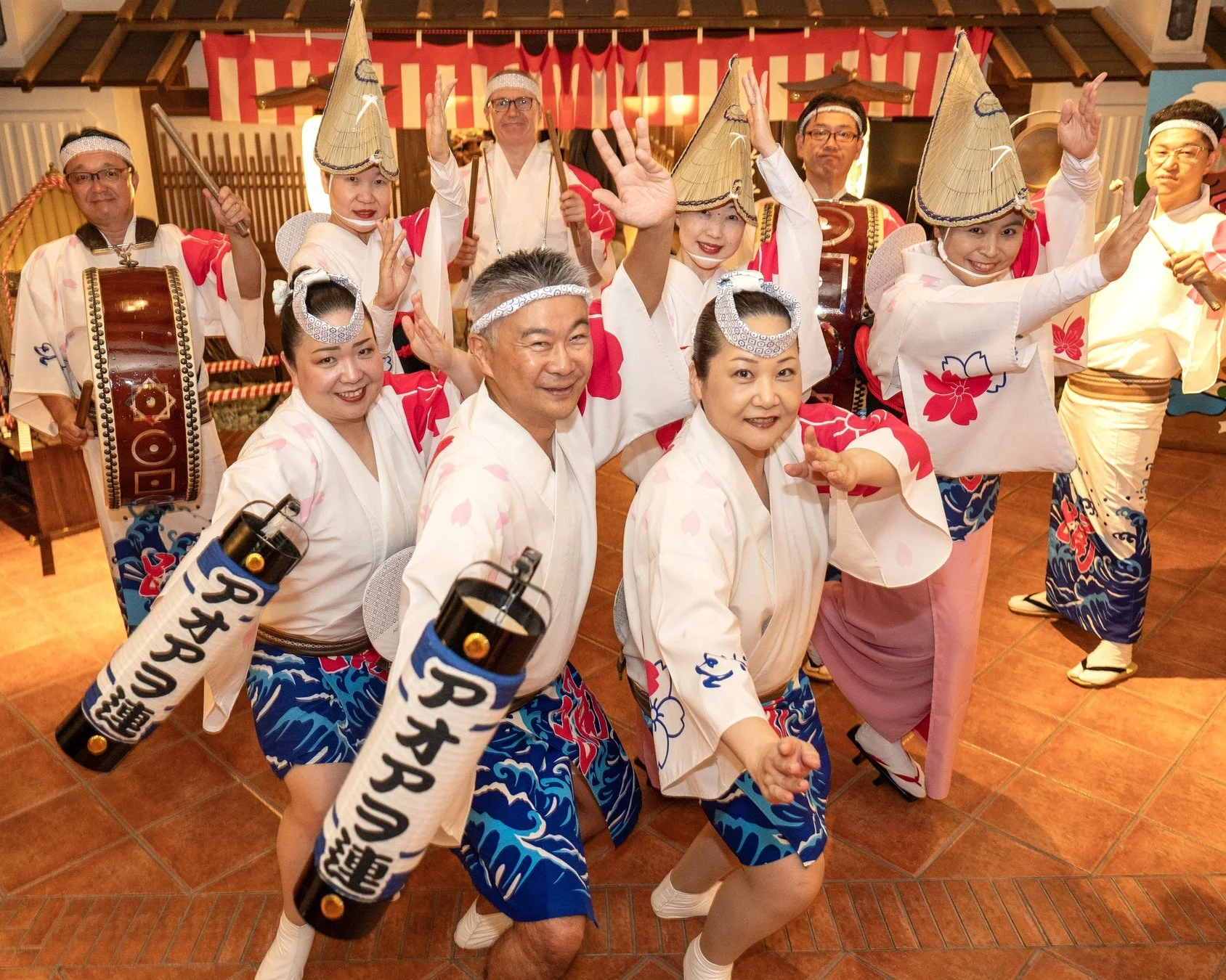 伝統的な衣装を身につけた人々が、阿波踊りのような活気あるパフォーマンスを披露しています。笑顔で踊る姿が印象的で、祭りの賑やかさを感じさせます。