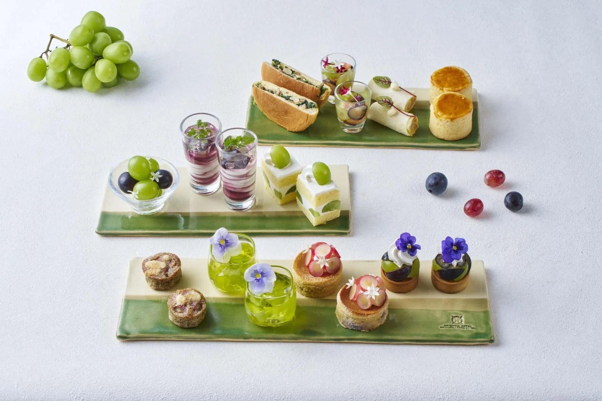 白と緑のプレートに美しく盛り付けられた、ぶどうをテーマにした多彩なスイーツと軽食のセット