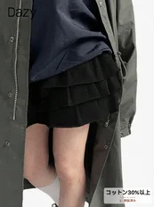 暗い色のロングコートと黒いフリル付きショートパンツを着用した人物のファッション画像