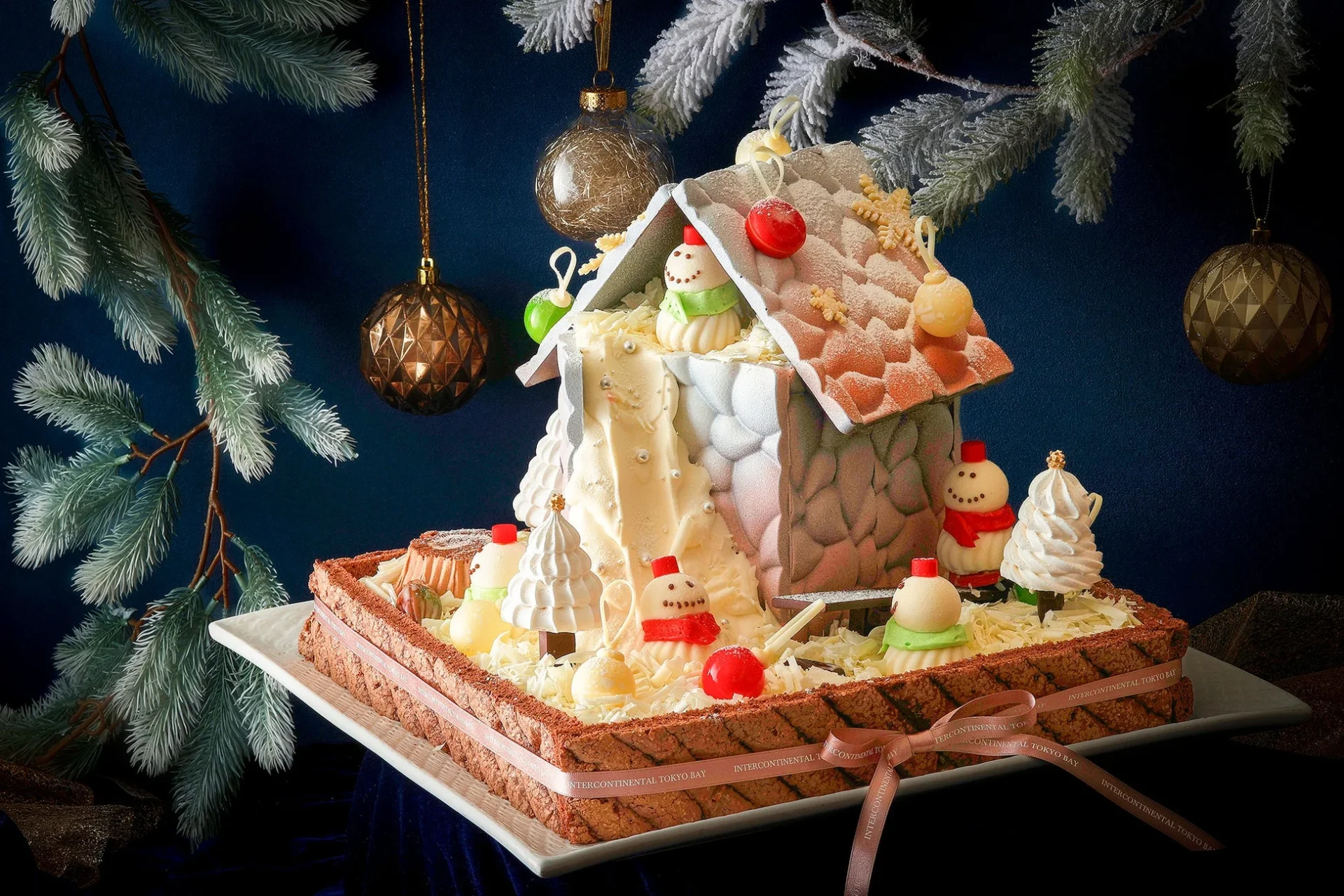 雪が積もった家を模した豪華なクリスマスケーキです。可愛らしい雪だるまやクリスマスツリーの形をしたデコレーションが施され、祝祭的な雰囲気を演出しています。