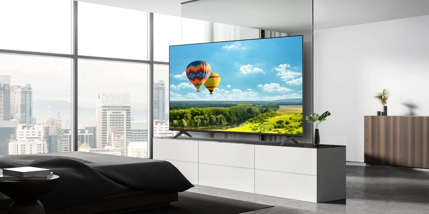 都会の眺望が広がるモダンな寝室に、熱気球の風景が映し出された大型テレビ
