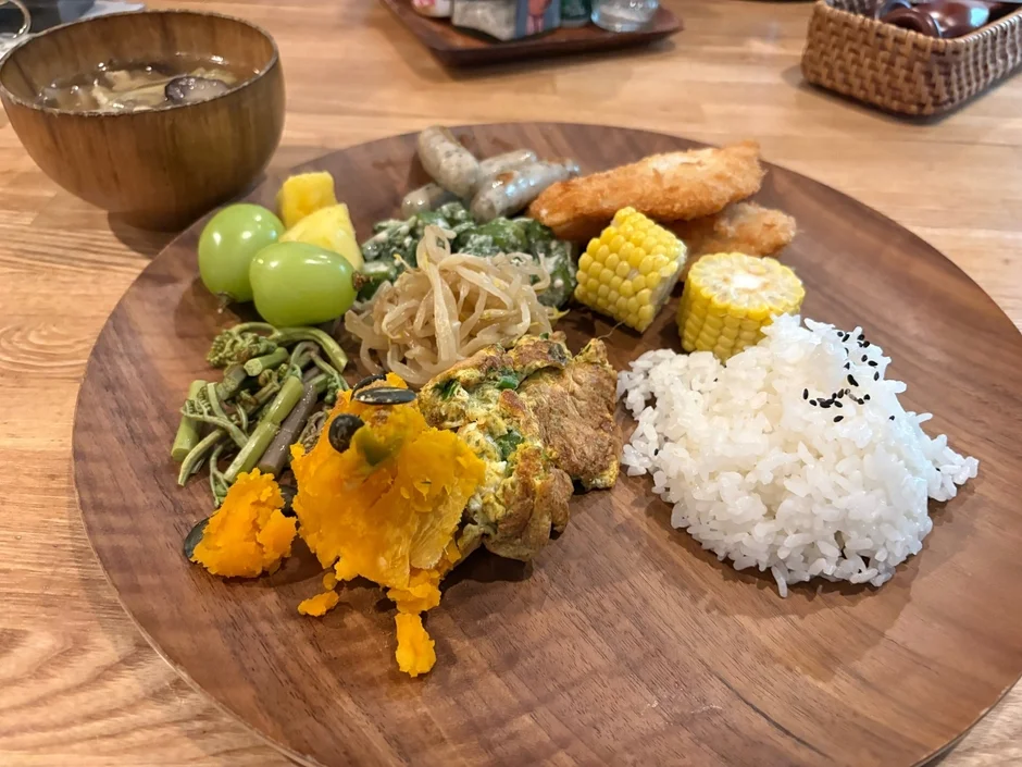 木製のプレートに盛られた、彩り豊かで品数の多い健康的な食事が写っています。