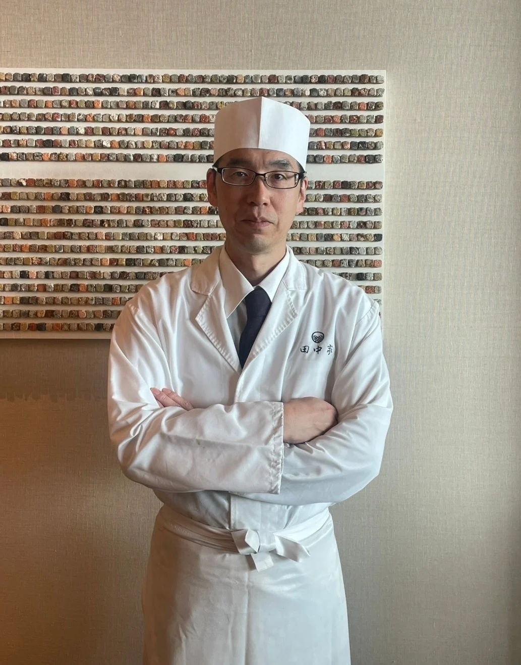 白いコック服を着て腕組みをした日本人男性シェフのポートレート