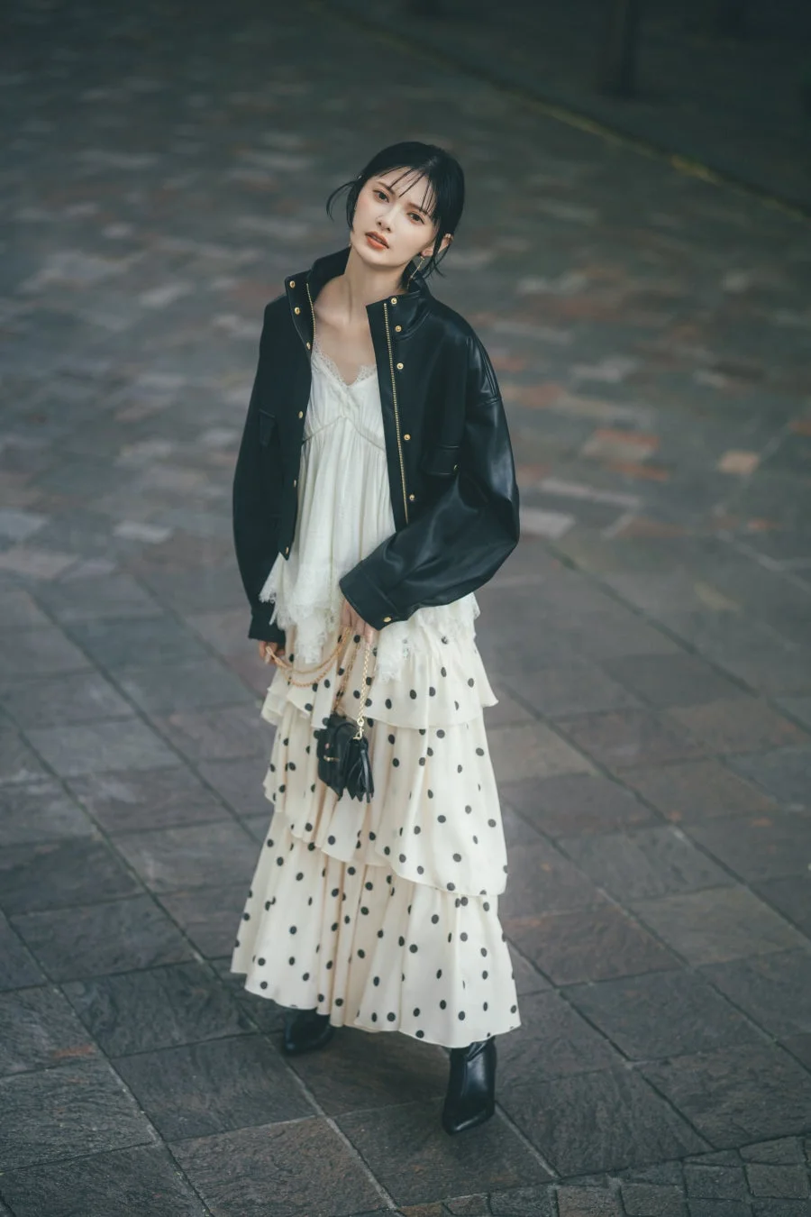 黒いレザージャケットとドット柄ティアードスカートの女性