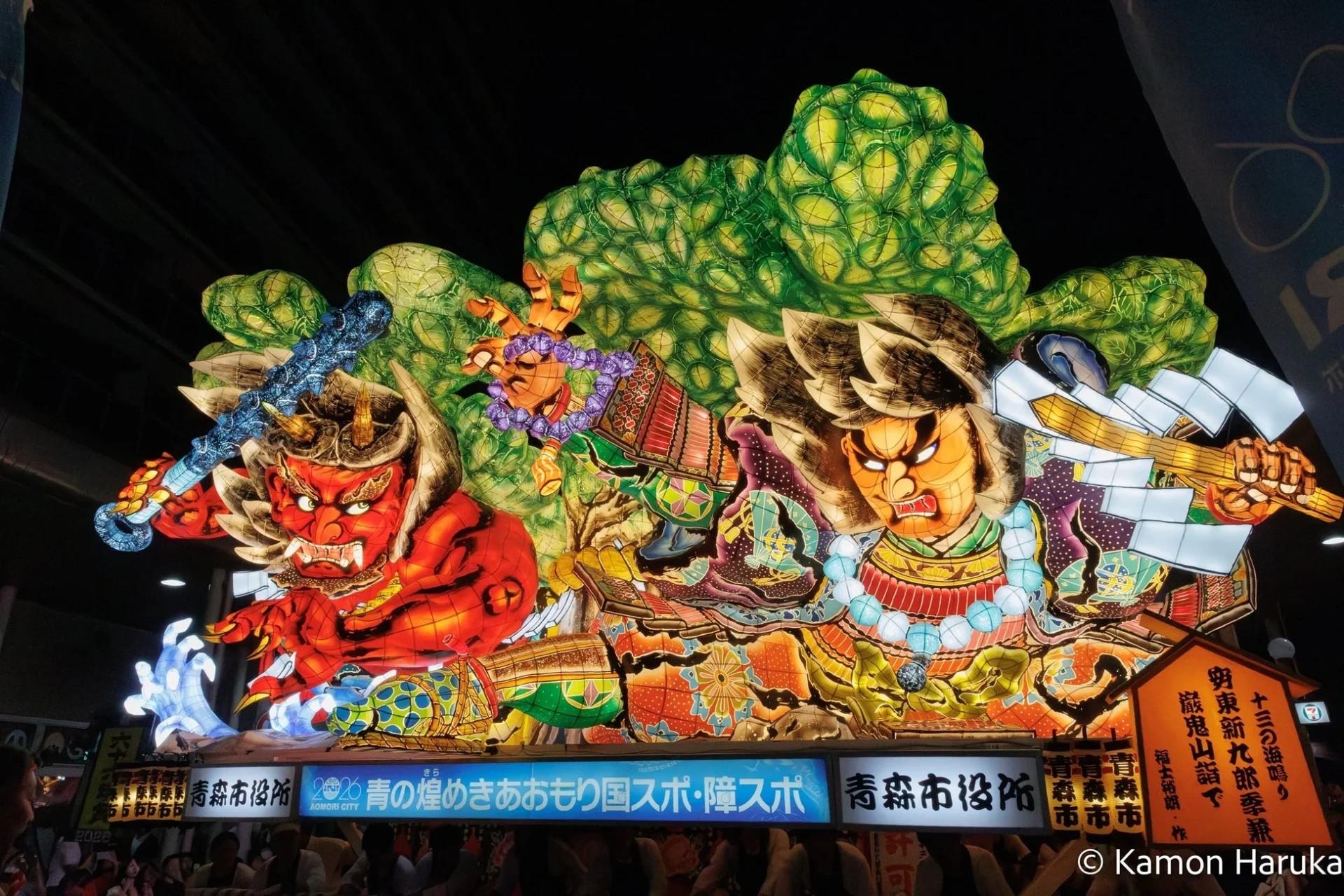 青森ねぶた祭りの夜、鮮やかにライトアップされた大型ねぶたが写っている。赤鬼と武者の迫力ある人形が特徴的で、祭りの熱気と伝統を感じさせる一枚である。