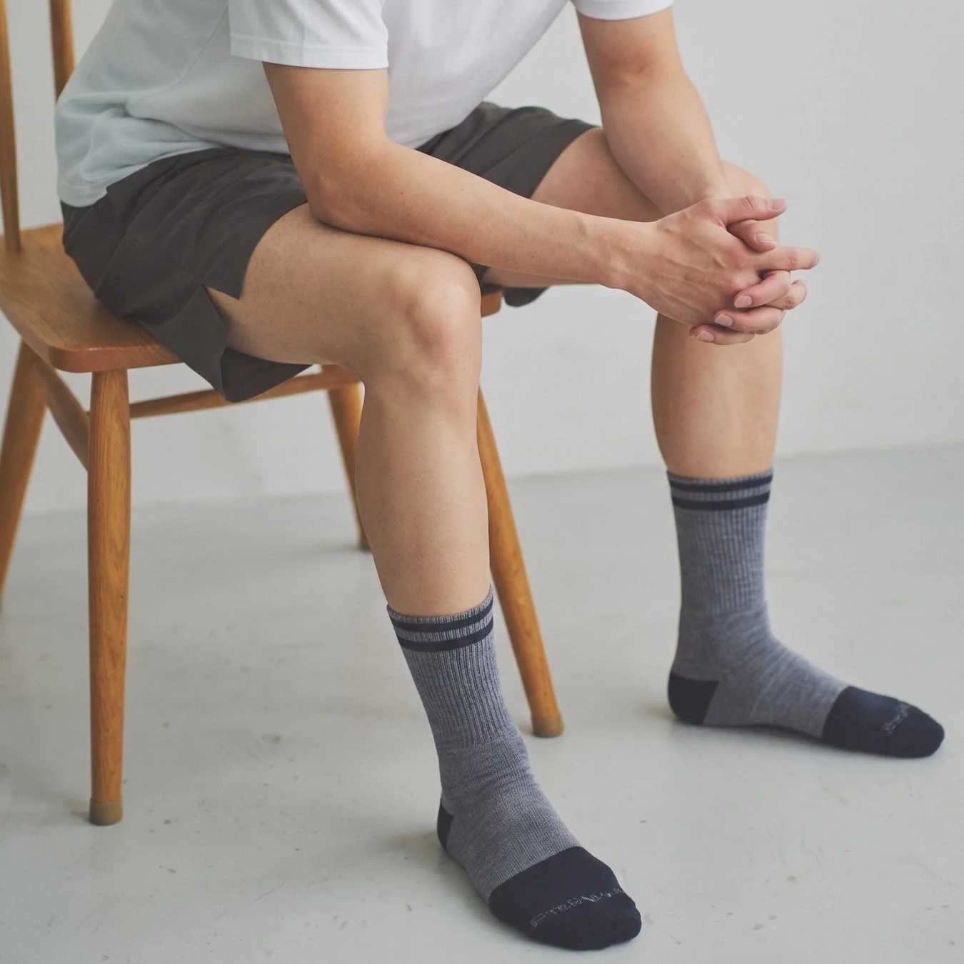 木の椅子に座った男性のソックス着用イメージ