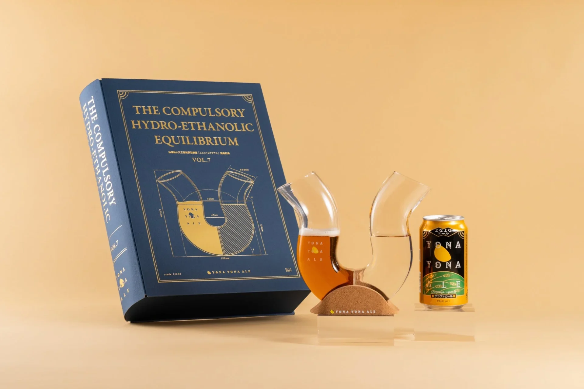 「よなよなエール」のビール缶と、特徴的な形状のビールグラス、そして「THE COMPULSORY HYDRO-ETHANOLIC EQUILIBRIUM VOL.7」と書かれた青い本型パッケージが写っています。グラスにはビールと水が注がれており、アルコール飲料の科学的なテーマを視覚的に表現した商品セットです。