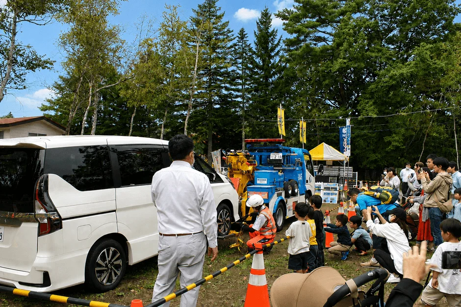 JAFのレッカー車による実演を見学する人々