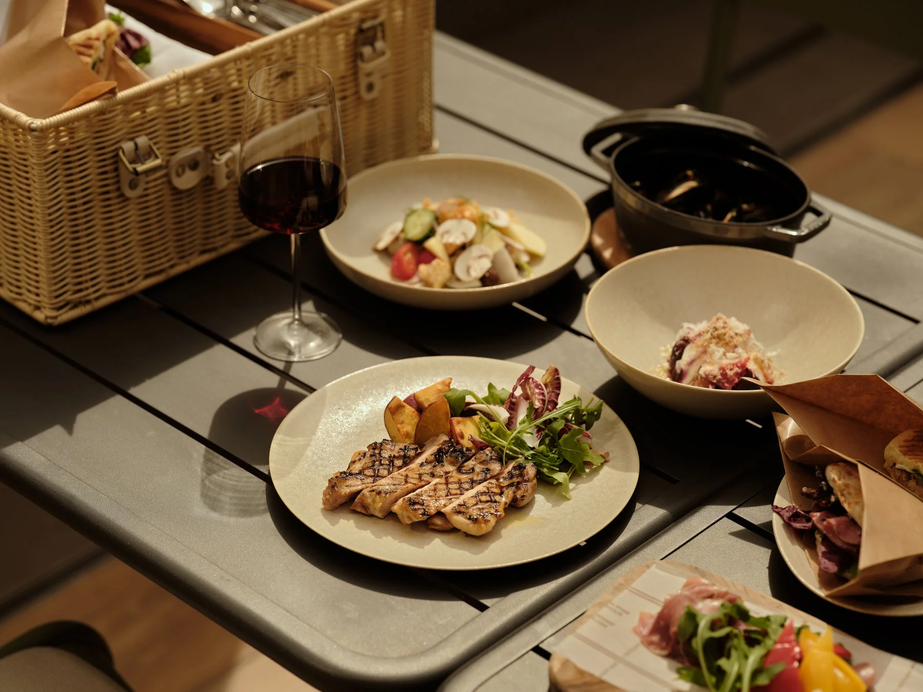 屋外のテーブルに並べられた料理とワイン