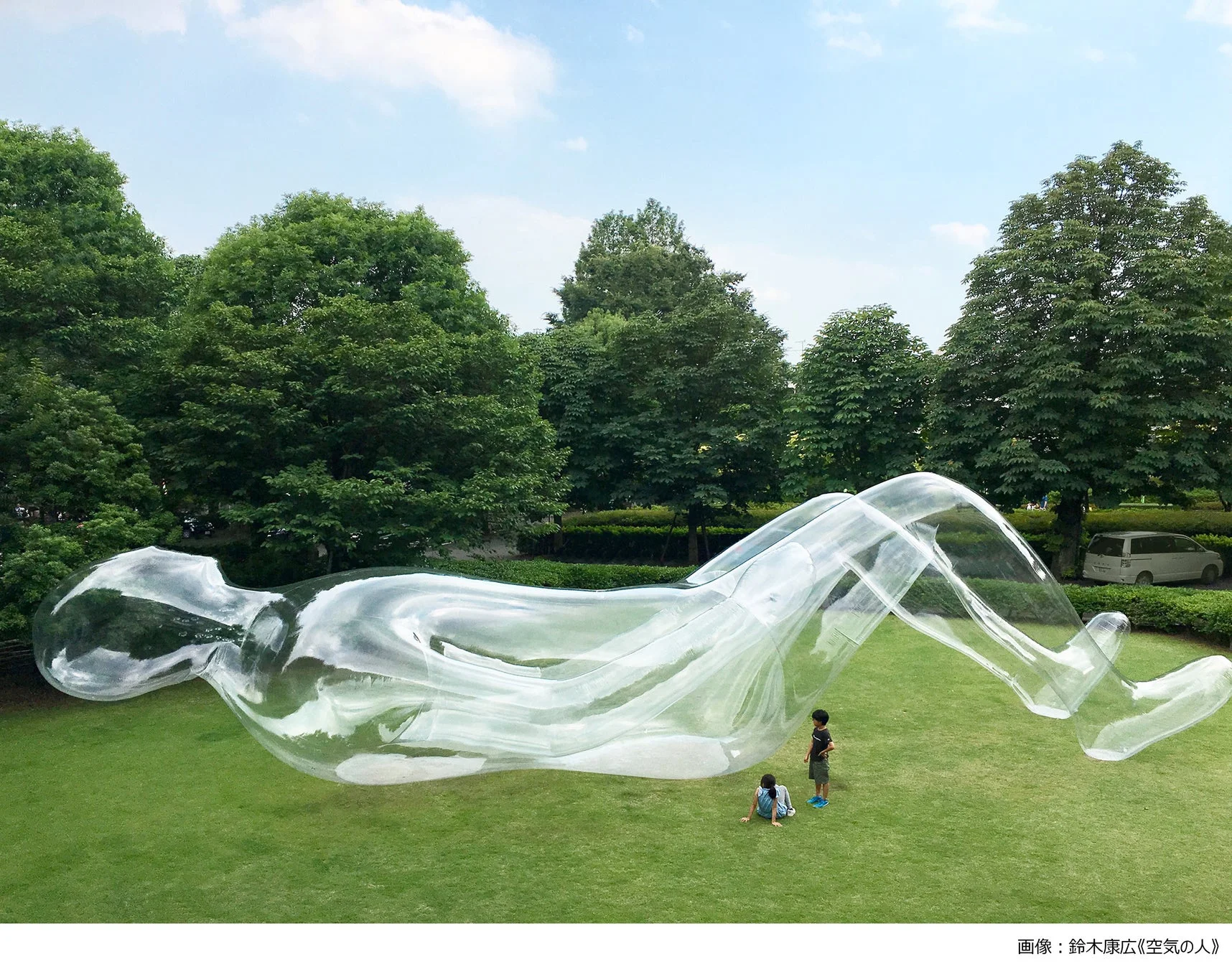 芝生の上に展示された透明な巨大な人型アート作品
