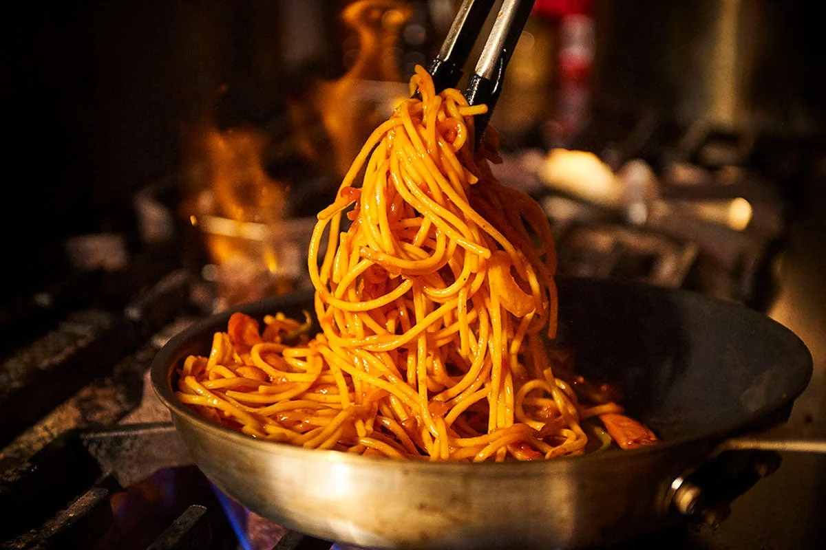 シェフがスパゲッティを炒めている様子