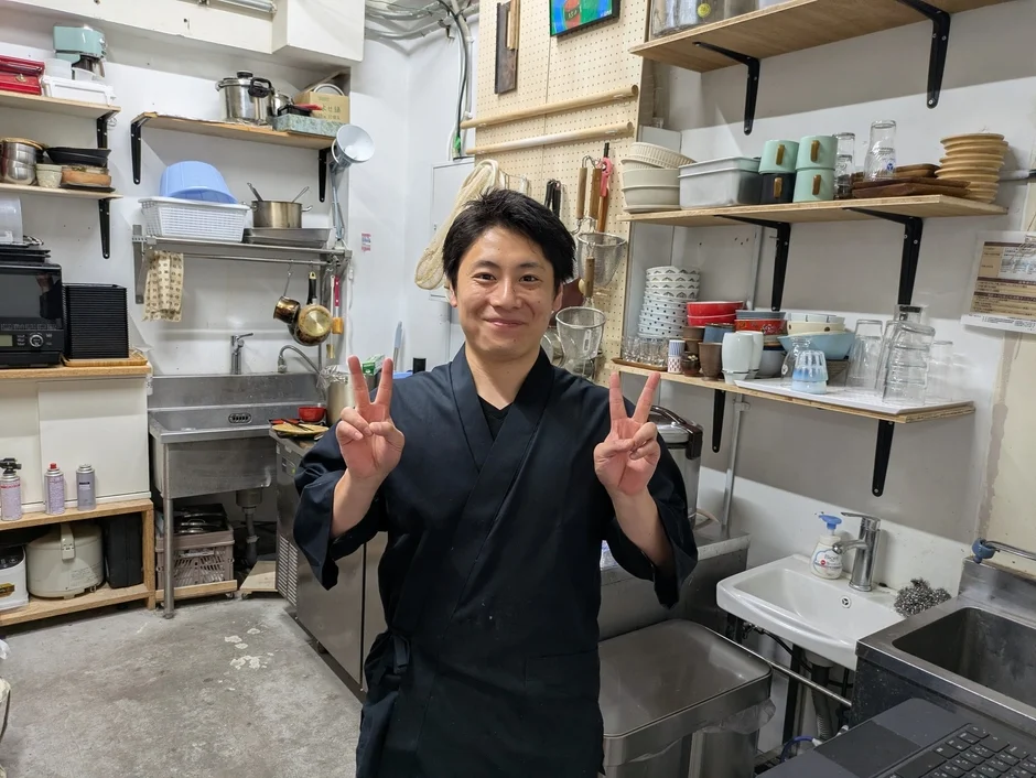 厨房でピースサインの男性
