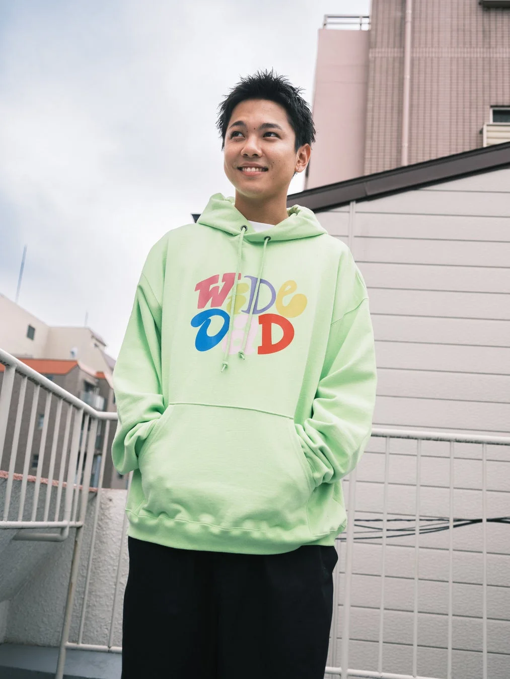 ライムグリーンのオーバーサイズパーカーを着た若い男性