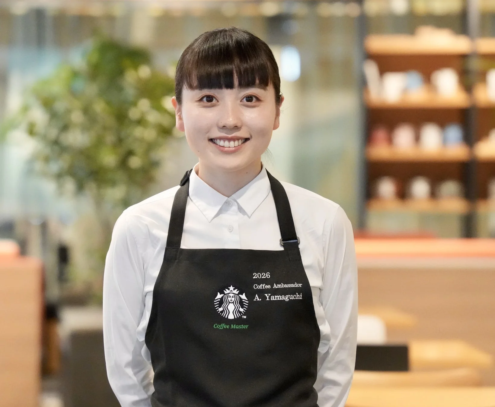 スターバックスのエプロンを着用し、笑顔で立つ女性のポートレート