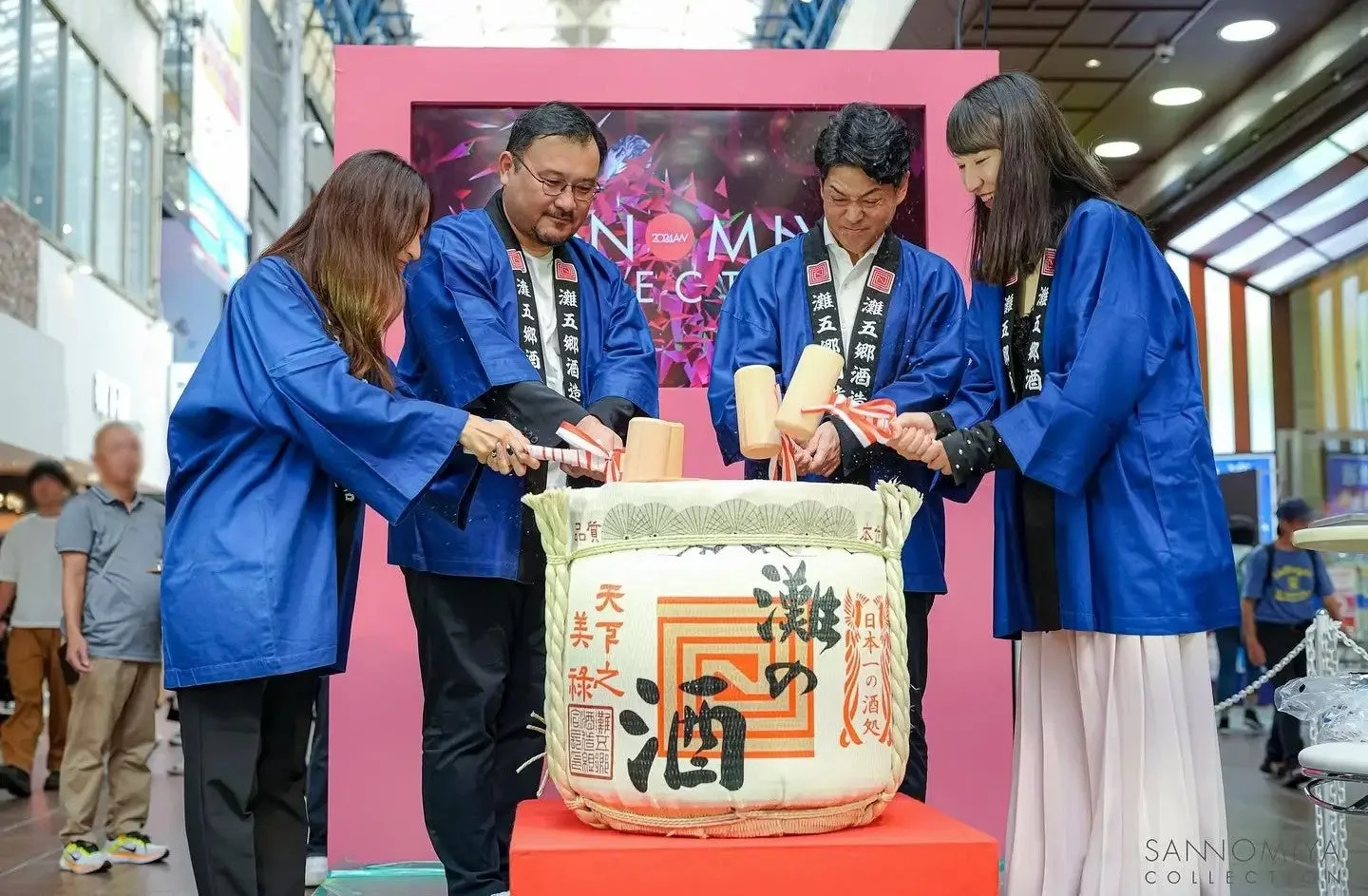 青い法被を着た4人が酒樽を木槌で叩く鏡開き