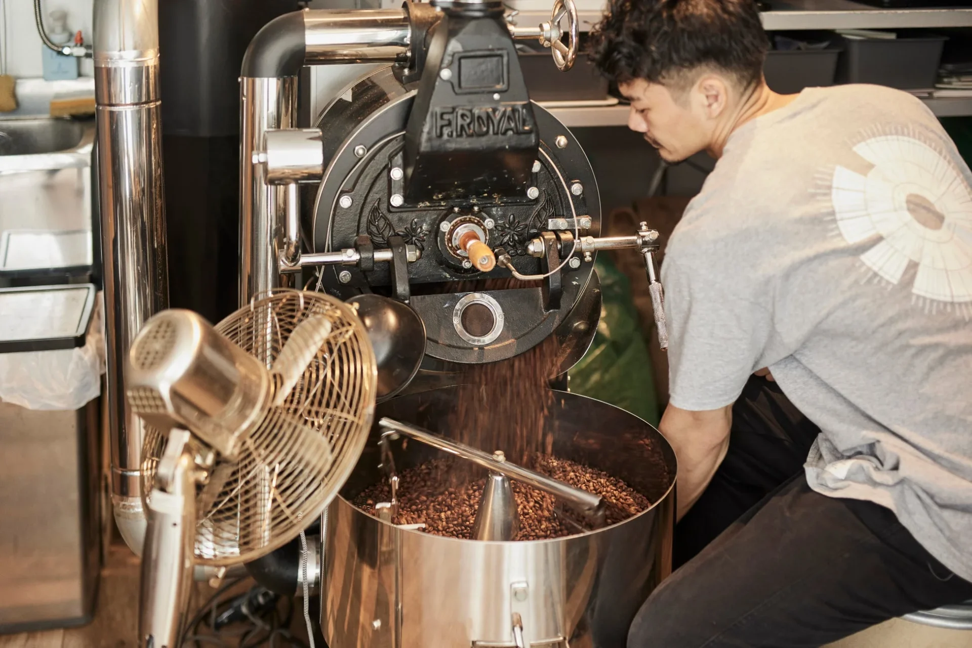 コーヒー豆の焙煎機を操作する男性の姿