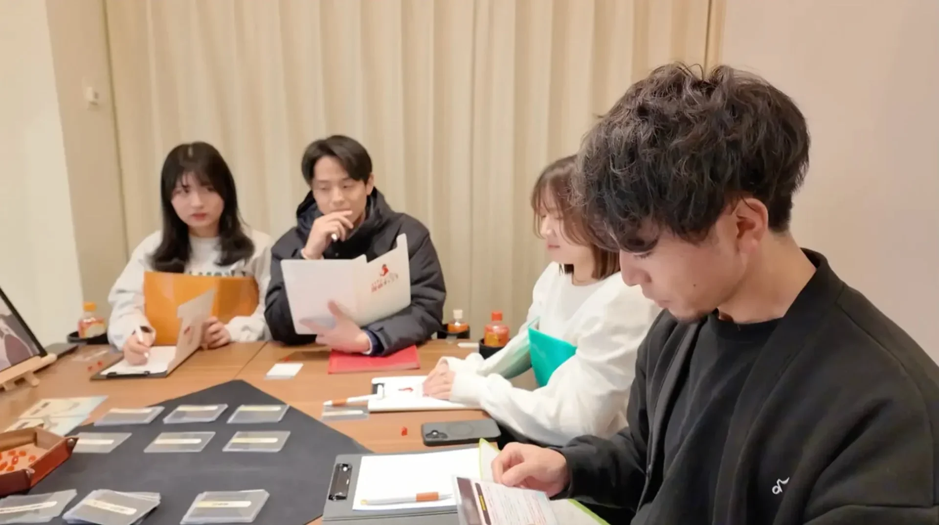 若者4人がテーブルを囲み、資料やカードを使って活動