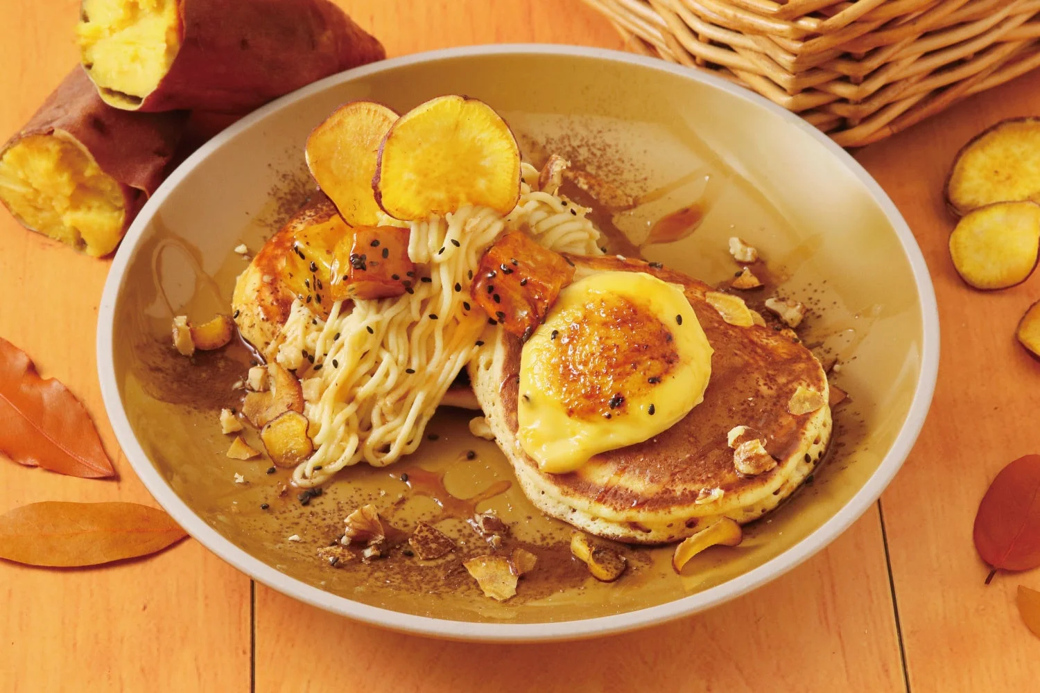 パンケーキに焼き色のついたクリーム、細い麺状のトッピング、さつまいもチップスが添えられています