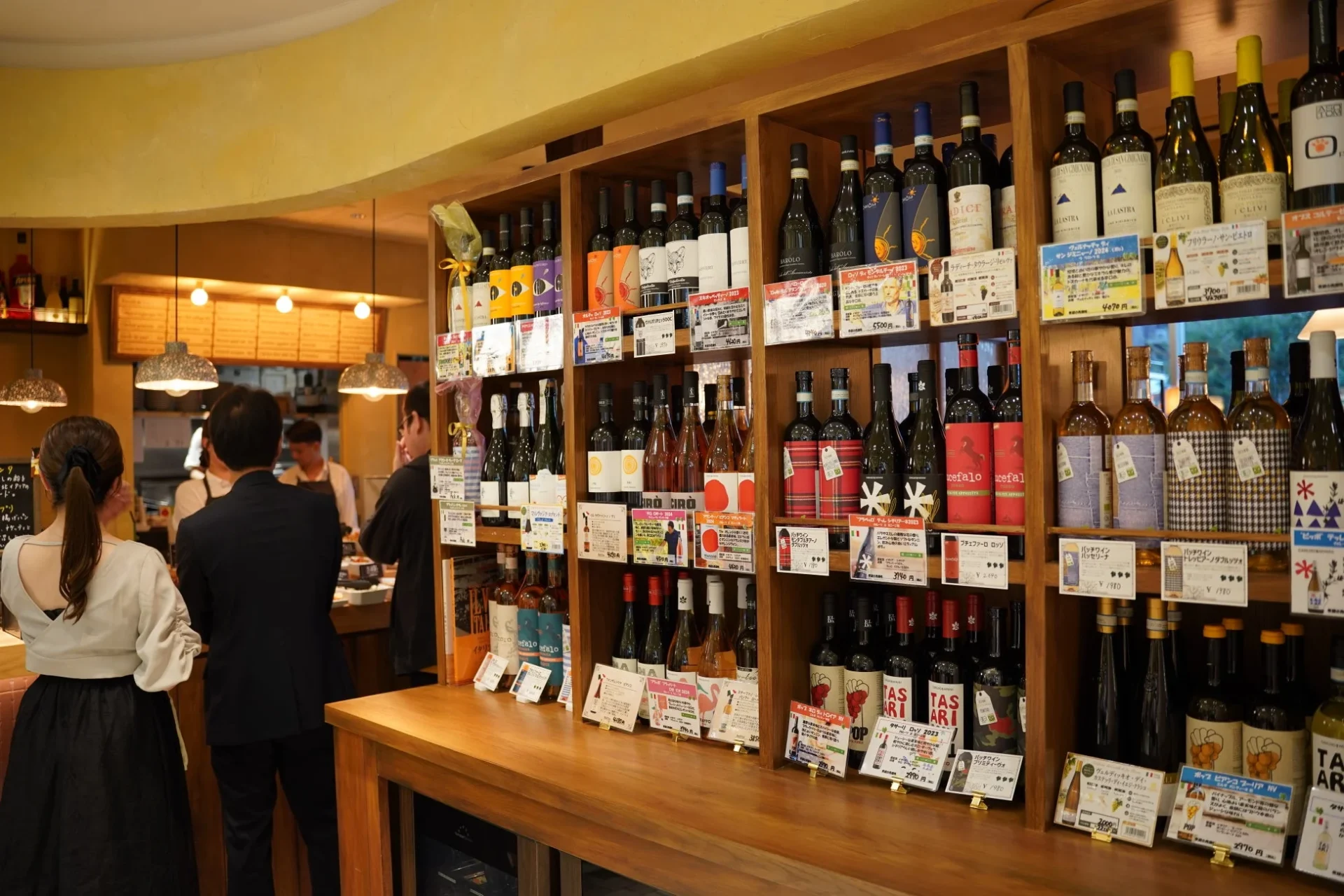ワインショップの店内で、木製の棚にイタリアワインのボトルが多数並べられています