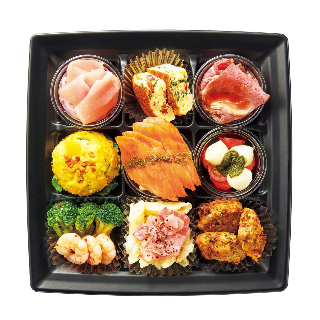 黒い仕切り付き容器に、ローストビーフ、スモークサーモン、カプレーゼ、ポテトサラダ、チキン、エビとブロッコリーなど、様々な種類のおかずが美しく盛り付けられたオードブル