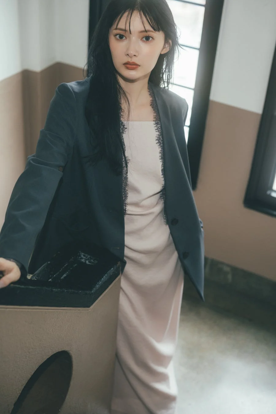 ダークグレーのジャケットとピンクベージュのレース付きドレスの女性