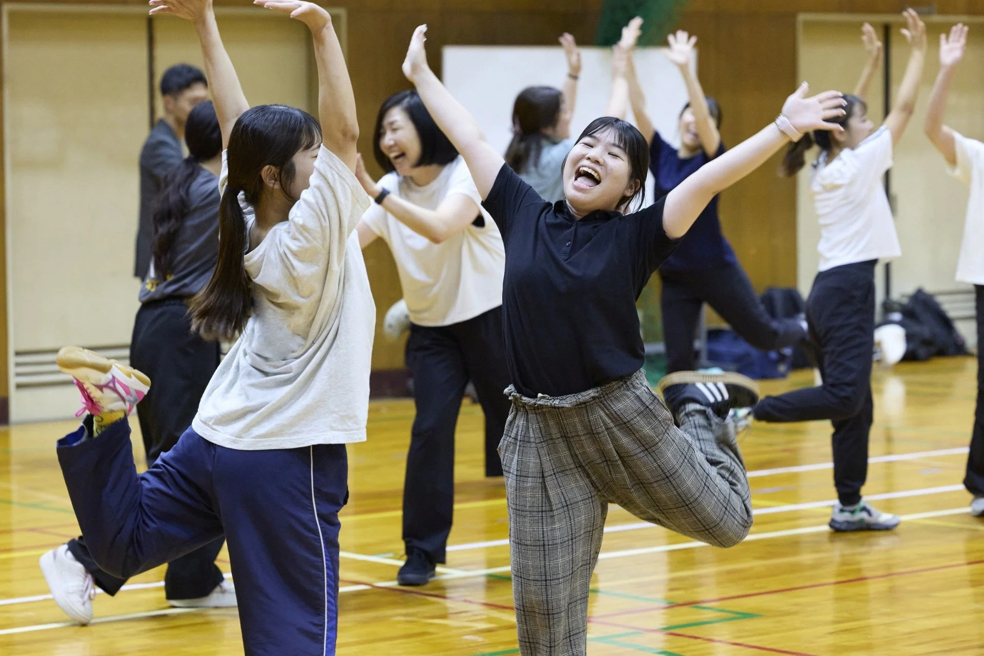 体育館で複数の若者が楽しそうに体を動かしている様子。